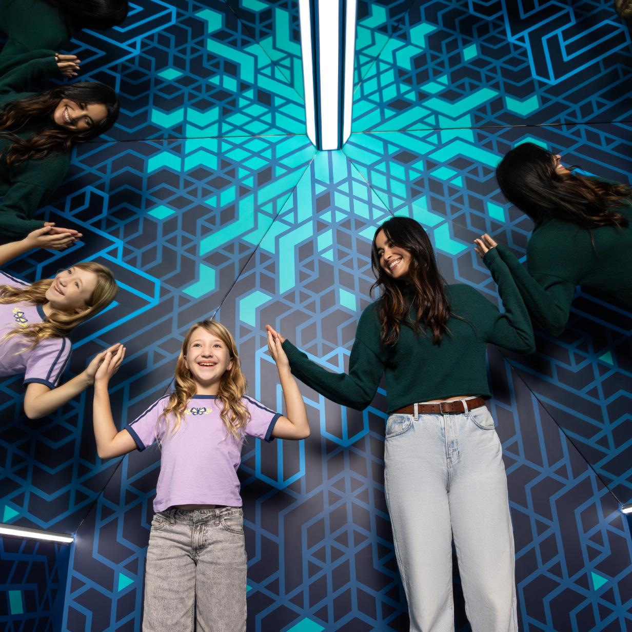 Visitors enjoying an illusion room experience with bold blue geometric visuals that distort perspective and space.